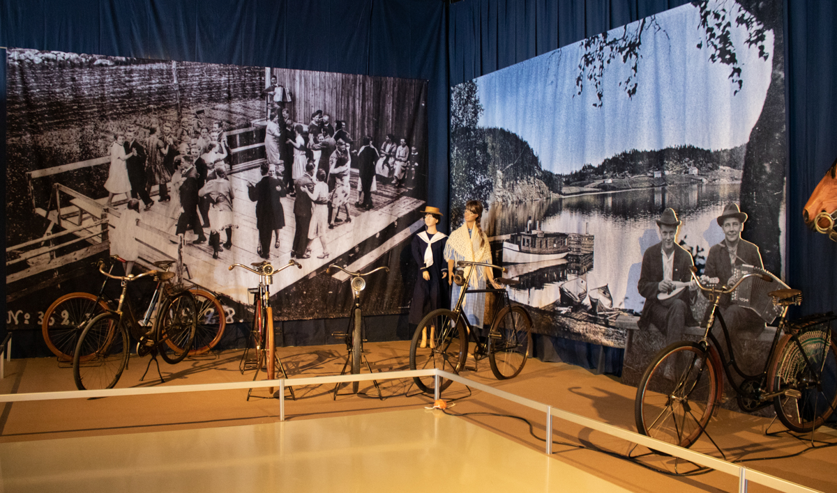 1920-luvun polkupyöriä näyttelyssä aikakauden tanssilavaa esittävän suurvalokuvan edessä.