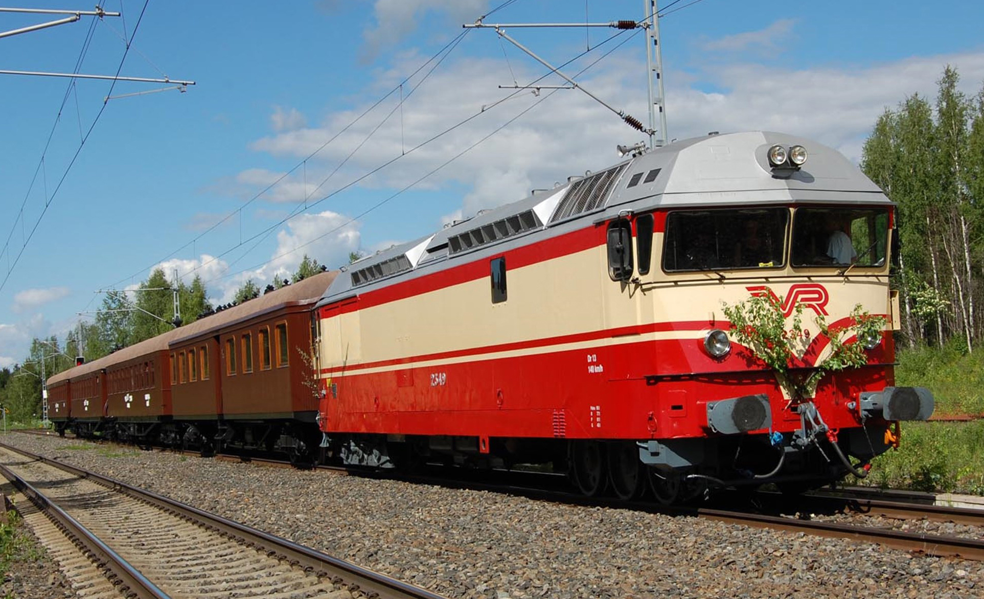 Punakeltainen dieselveturi, jonka perässä ruskeita puukorisia matkustajavaunuja.